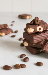 pieces of chocolate with hazelnuts and coffee beans on a marble table