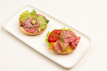 Sandwich with ham, salami, cheese and lettuce on a white background. Copy space, white background.