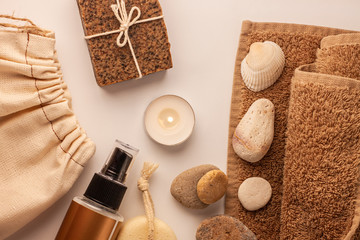 Fototapeta na wymiar Spa and wellness concept, natural coffee scrub soap in cotton eco bag,essential oil cosmetic,peeling sand stone,towel,wooden haircomb.Beige dayspa set.Pastel bathroom accessories and products top view