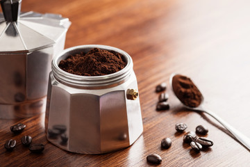 ground coffee in Moka pot and on wooden table preparing coffee to brew.