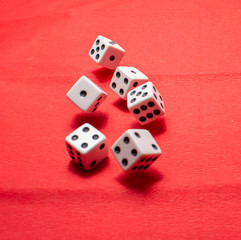 Hand throwing dice, hoping for the best odds. Six dice on red background