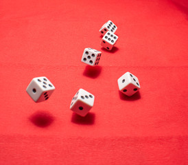 Hand throwing dice, hoping for the best odds. Six dice on red background