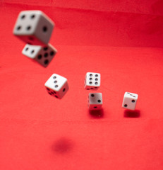 Hand throwing dice, hoping for the best odds. Six dice on red background