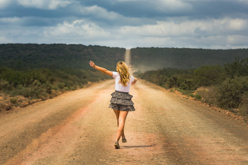 Happy woman walking and jumping on a long abandon country road enjoying and celebrating her freedome