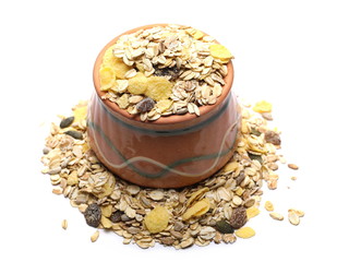 Muesli mixture of wholegrain foods, cereals, seeds and raisins in clay bowl isolated on white background