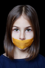 Unhappy girl with sticky tape over her mouth. Violation of human rights. Kidnapping.