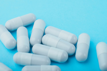 White capsules medications or supplements on a colored background