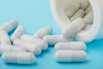 White capsules medications or supplements on a colored background