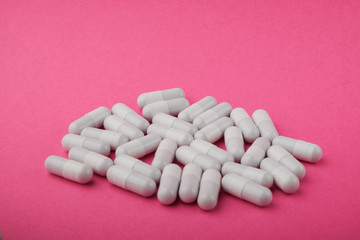 White capsules medications or supplements on a colored background