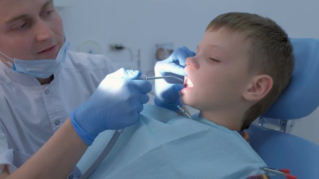 Preparing for fluoridation of teeth after hygienic cleaning of the oral cavity. Dentist drying child boy teeth with air to cover it with fluoride. Fluoridation of teeth after cleaning for protection.