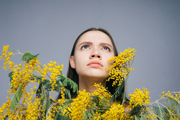 the girl inquires anxiously looking up peeking from behind a bouquet of mimosa