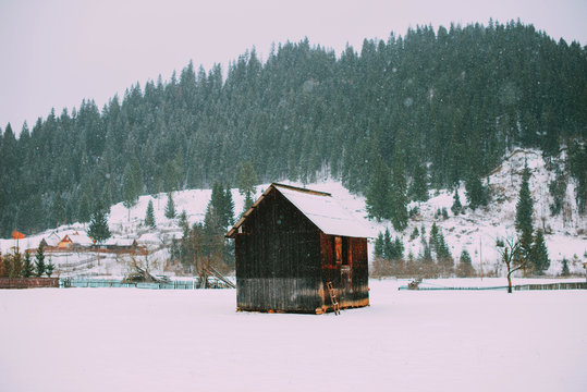 Winter landscape in mountains during snow with old wood house