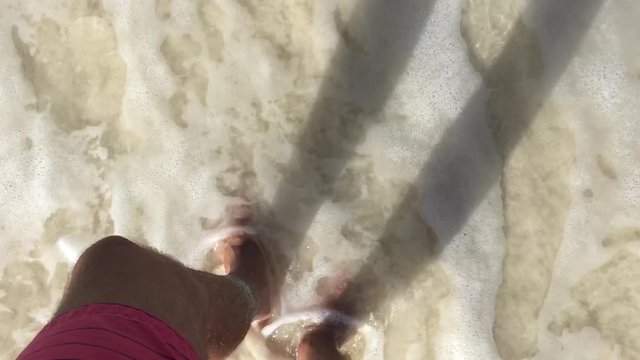 waves from clean ocean paradise gently covering a guy feet standing in the sand at the tropical beach, slow motion cinematic