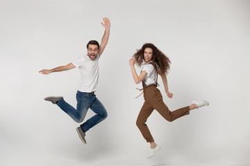Fototapeta na wymiar Joyful young man and happy millennial girl jumping high.