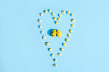 Easter Eggs. Yellow eggs on a blue background. heart made of sweet sweets. Two eggs, a symbol of love, a pair of lovers. Love concept, valentines day, easter.