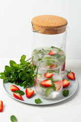 carafe and glasses with a drink with strawberries and mint