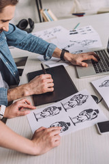 cropped view of animator pointing with finger at cartoon sketch near coworker