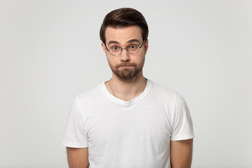 Millennial dissatisfied serious bearded man in eyeglasses squeezing lips.