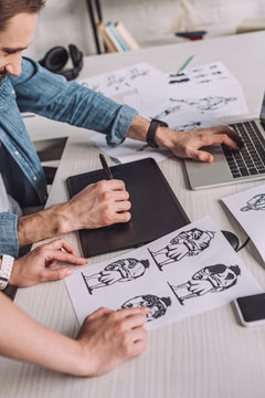 cropped view of animator pointing with finger at cartoon sketch near coworker