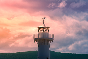 Close up of old white lighthouse tower with epic sunset sky on the background
