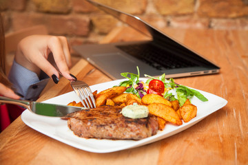 Young woman eating grilled steak in restaurant