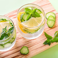 Healthy refreshing summer cocktail or mocktail without alcohol with lemon and cucumber. Summer detox drink on fresh green background, healthy living, top view