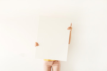Young pretty woman hold blank canvas with empty mockup copy space. Minimal art concept.