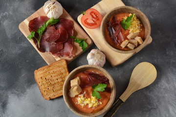 Traditional Spanish andalusian tomato cream soup Salmorejo served with egg, ham jamon, bread in woooden bowl. Summer cold soup concept
