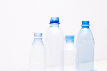 different plastic bottles on a white background, small bottles, bottled water, empty bottles on a beige background, copy space, blue plastic containers, the problem of waste disposal and recycling