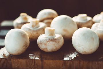 champignon mushrooms on a wooden board on a dark background