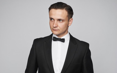 Serious young man in tuxedo is looking away isolated