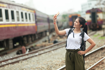 asian girl are taking pictures at the train station before traveling by train, destination nature trip in summer