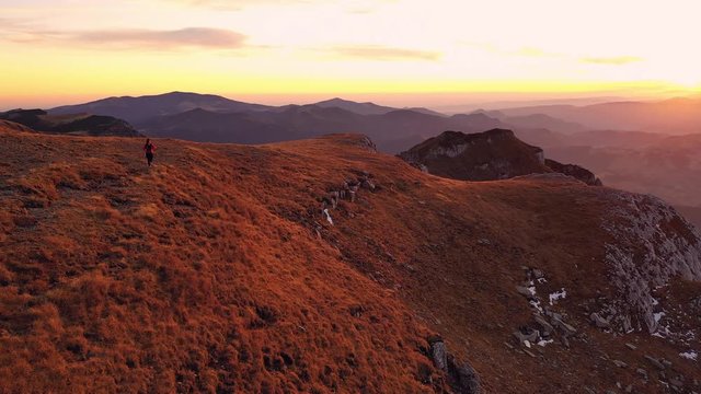 4k drone clip with hiker trekking on a huge mountain valley in Bucegi mountains, during magical golden hour light in autumn season in Romania