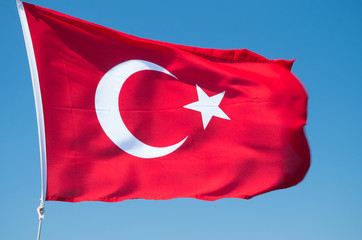 Turkish flag flutters against the blue sky. National flag of the Republic of Turkey.