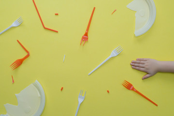 Plastic garbage and children's hand on yellow.