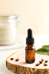 Cosmetic oil, skin care product for face and body with coffee extract. Glass bubble, next to coffee beans.