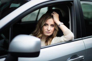 Fototapeta na wymiar Sad woman sitting in car on a driver's seat