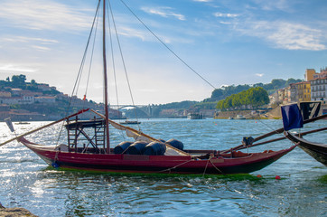 Naklejka na ściany i meble Portugal, Porto in summer, panoramic view of Douro river, red wooden boat with wine port barrels close-up, the banks of the river Douro