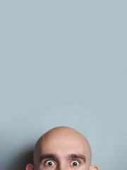 Emotional portrait of surprised bald man.