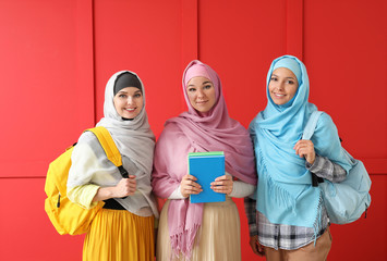 Female Muslim students on color background