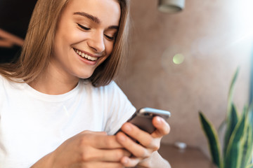 Fototapeta premium Photo of joyful young woman using cellphone and smiling