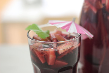 glass of red wine sangria with fruit and ice with summer hat