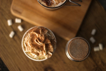 coffee with whipped cream and cacau on wooden background and marshmallows