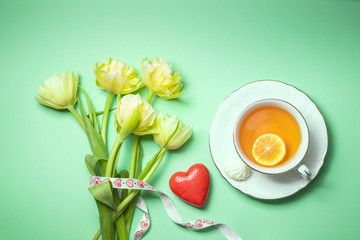 Bouquet of yellow tulips and a cup of tea with lemon close-up. Composition for Valentine's Day, birthday.