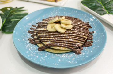 blue plate with pancakes with chocolate and banana