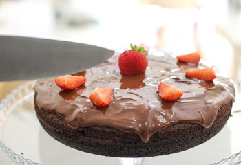 beautiful chocolate cake with chocolate icing and strawberries cuting