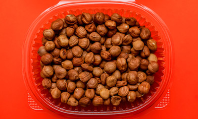 Nuts in a bowl on a red background. Hazelnuts, food, snack.