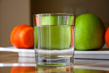on the table a glass of clean water on a background of fruit