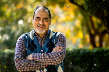 Confident senior man with arms crossed at park