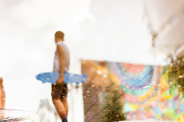 A boy holding a skiing board reflected in a pool of water. Concept of summer sports, vacation, weekend and healthy lifestyle. Blurred, no focus